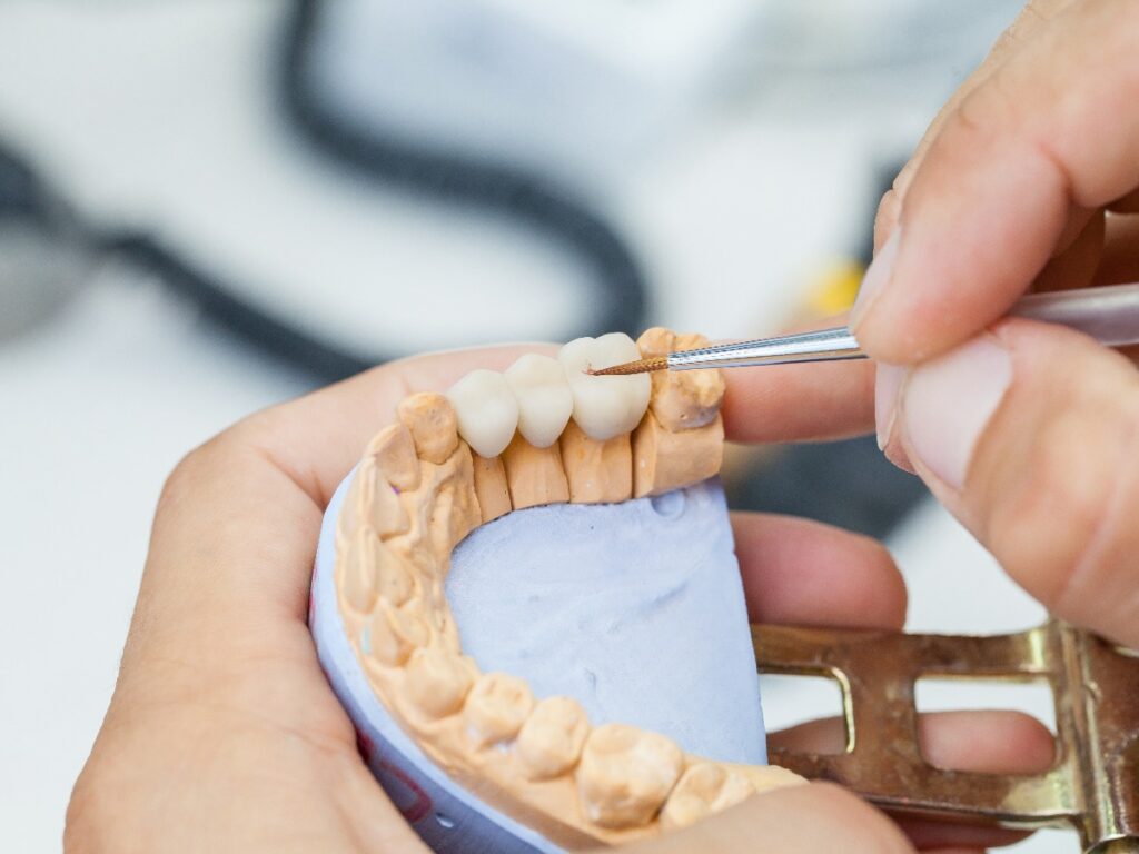 dental technician works by brush with jaw model