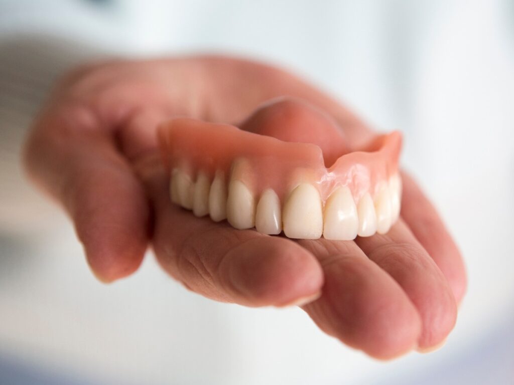 closeup of womans hand holding a teeth denture