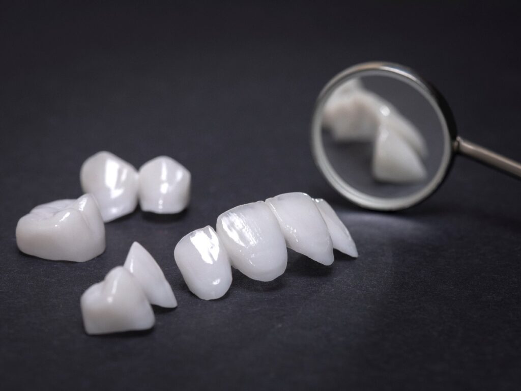 Dental mirror and zircon dentures on a dark background - Ceramic veneers - lumineers