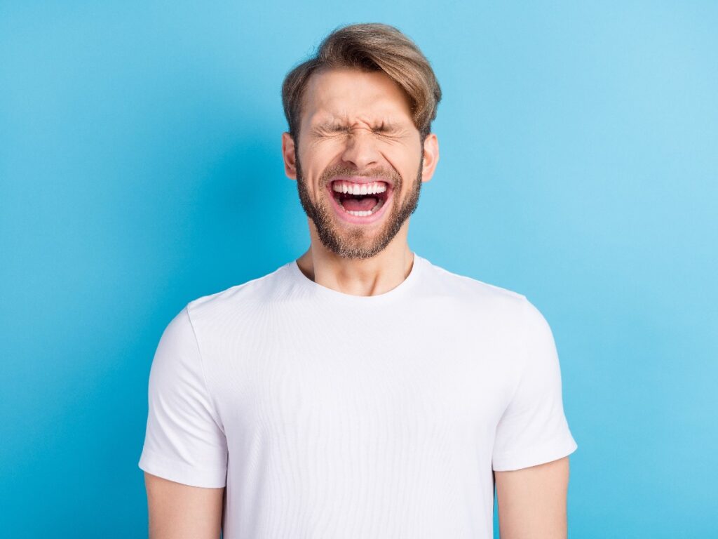 Photo portrait of young man in casual t-shirt laughing with opened mouth isolated bright blue color background