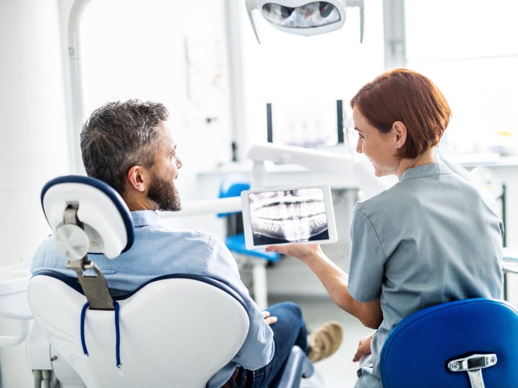 Rear view of man and dentist in dental surgery, annual check-up.